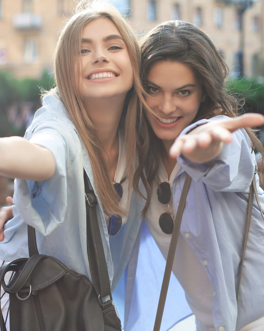 Two smiling young women standing together in the city