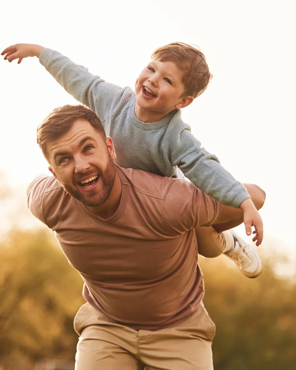 Father carrying a smiling child outdoors