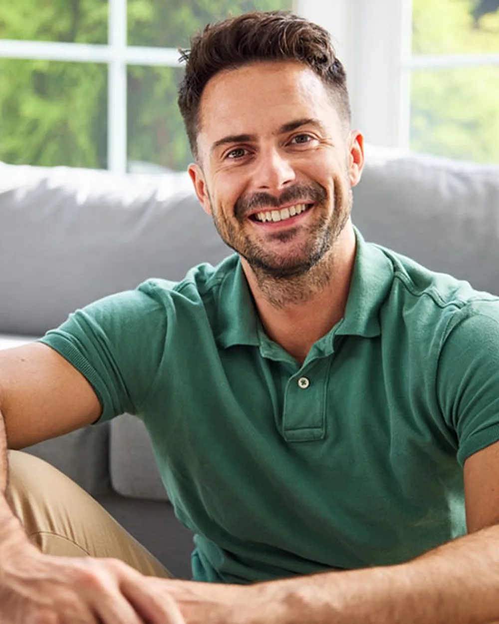 Smiling man in a green polo seated at home
