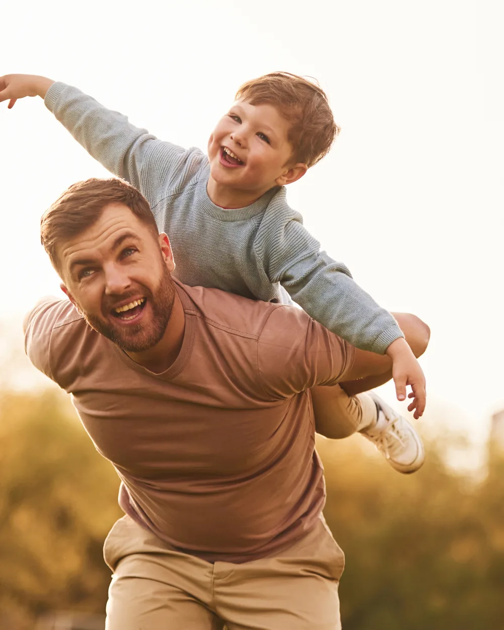 Father carrying a smiling child outdoors